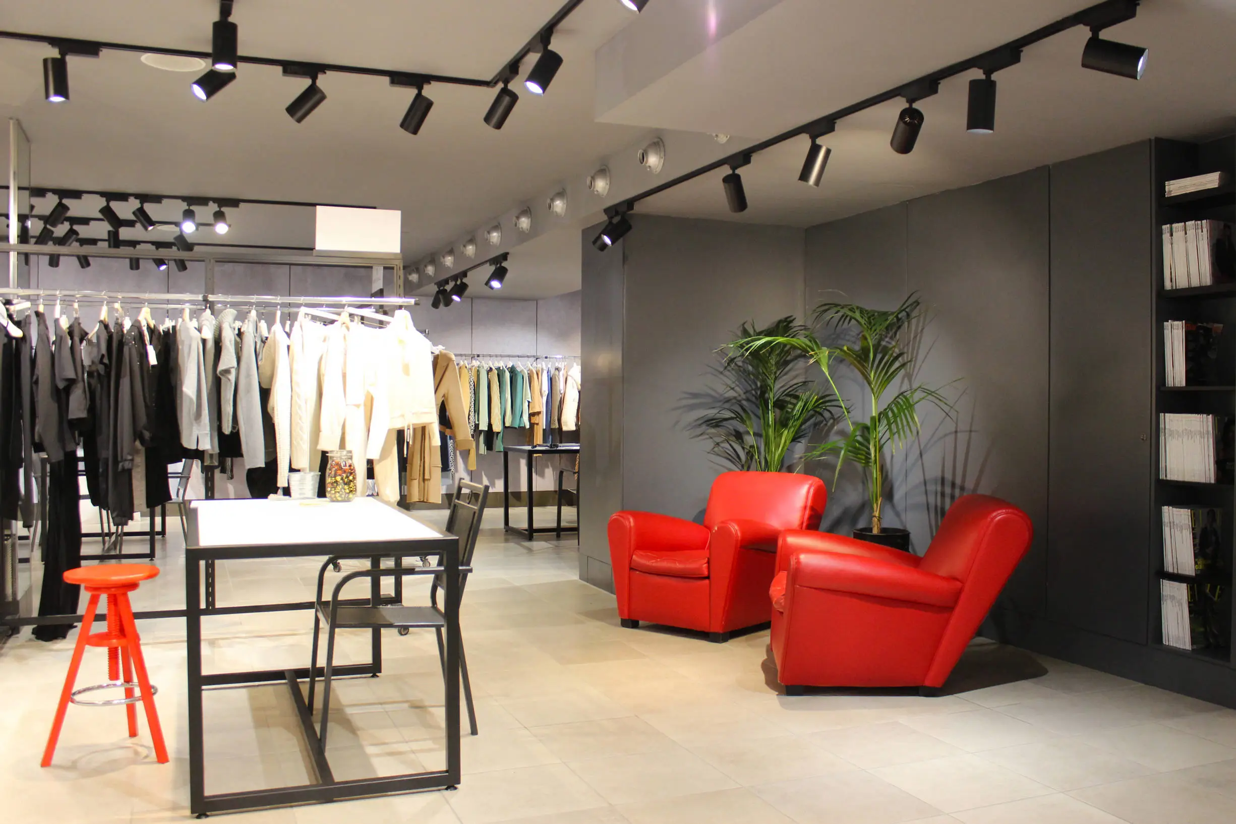 stanza showroom badii fashion group con due poltrone rosse tavolo e rail con i capi di abbigliamento