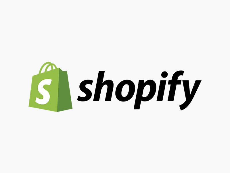 logo shopify nero su sfondo grigio con busta del logo verde con la "s" bianca utilizziao per un articolo di e-commerce abbigliamento. Magazine Badii Fashion Group black shopify logo on gray background with green logo envelope with white "s" used for an e-commerce clothing item. Magazine Badii Fashion Group eng