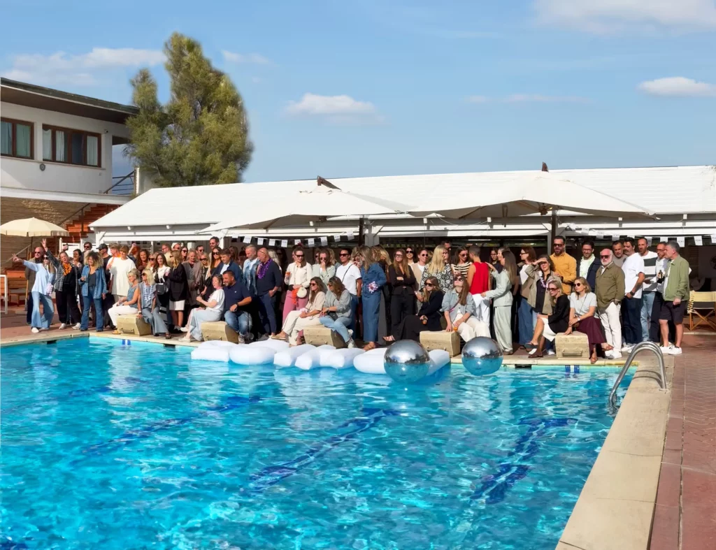 una piscina con un gruppo di persone che fa una foto ricordo per la festa Ichi Party 25 anni. sullo sfondo nuvole scure che indicano il tempo non proprio sereno.